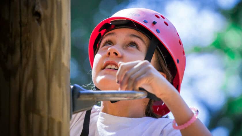 Close up of girl wearing helmet while climbing a pole