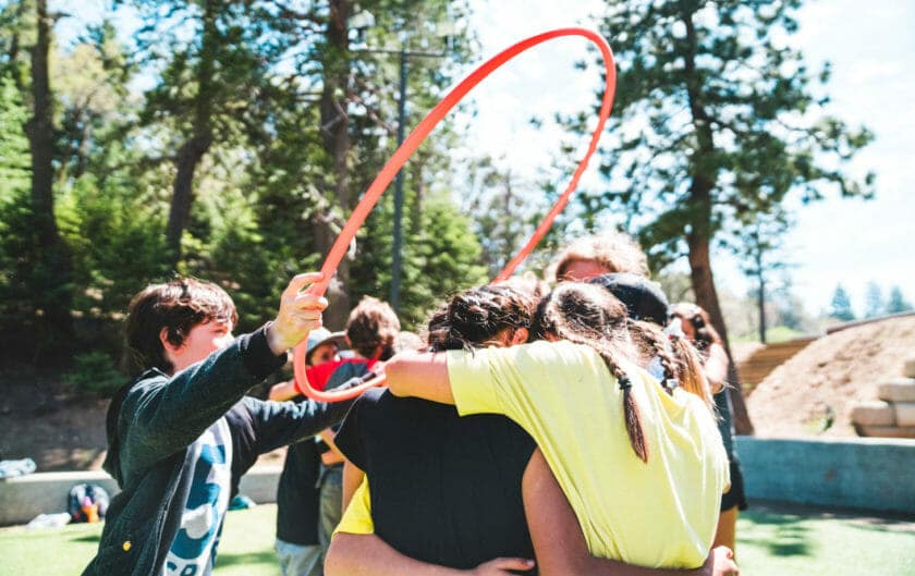 Student puts hula hoop over group during team building exercise