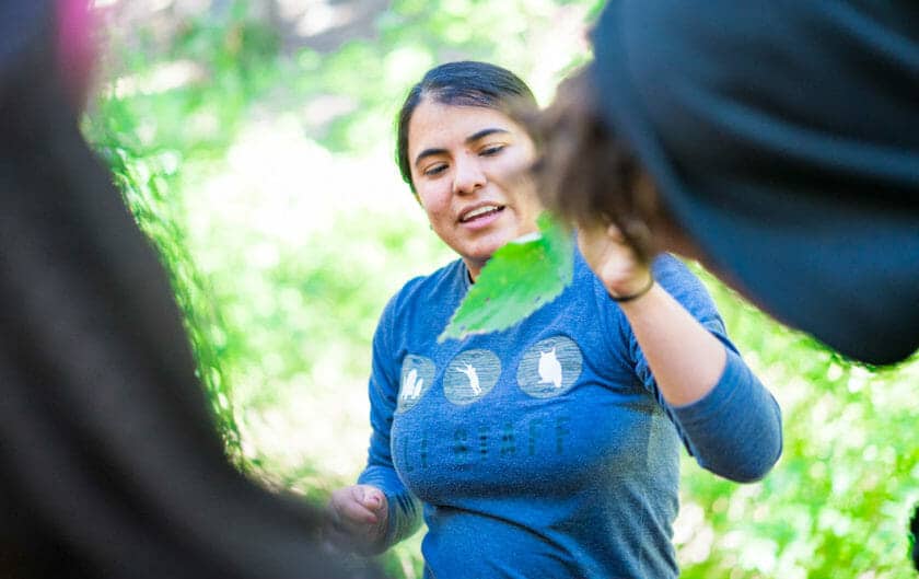 Pali instructor holds leaf during forest ecology lesson